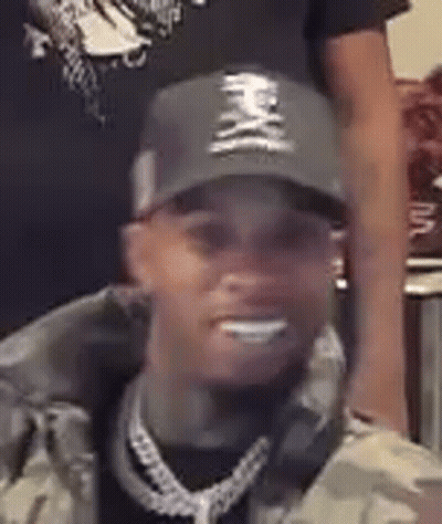 A Close Up Of A Man Wearing A Hat And A Chain . GIF