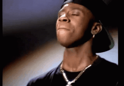 A Close Up Of A Man Wearing A Hat And A Necklace With His Eyes Closed GIF