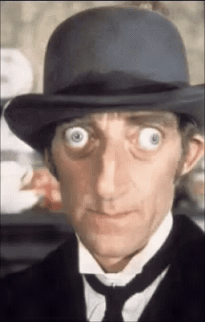 A Close Up Of A Man Wearing A Hat And Tie With His Eyes Wide Open . GIF