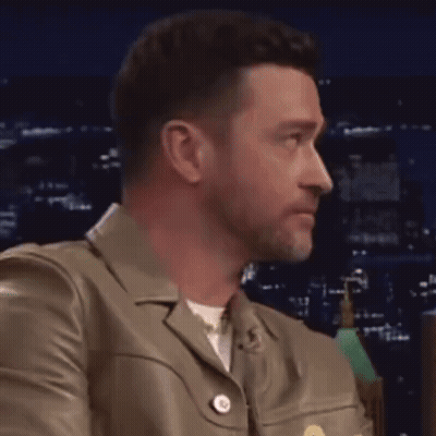 A Close Up Of A Man Wearing A Leather Jacket Looking To The Side . GIF