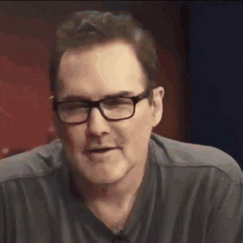 A Close Up Of A Man Wearing Glasses And A Black Shirt GIF