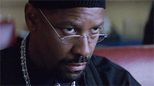 A Close Up Of A Man Wearing Glasses And A Chain Around His Neck GIF