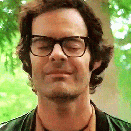 A Close Up Of A Man Wearing Glasses And A Green Jacket GIF