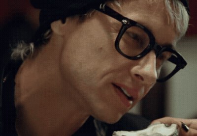 A Close Up Of A Man Wearing Glasses And A Hat GIF