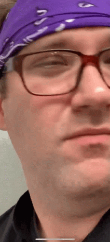 A Close Up Of A Man Wearing Glasses And A Purple Headband GIF