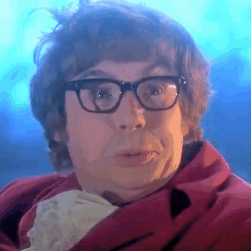 A Close Up Of A Man Wearing Glasses And A Red Jacket GIF