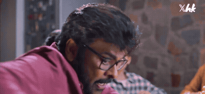 A Close Up Of A Man Wearing Glasses And A Red Shirt With Xhk Written On The Bottom GIF