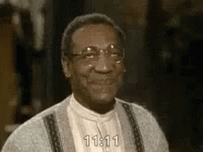 A Close Up Of A Man Wearing Glasses And A Sweater Smiling . GIF