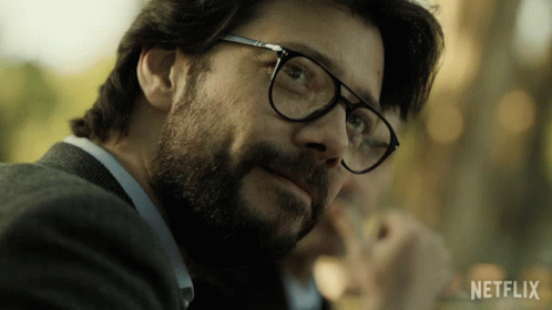 A Close Up Of A Man Wearing Glasses With A Netflix Logo In The Background GIF