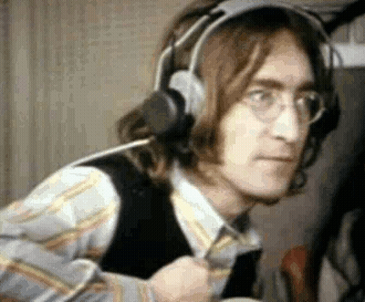 A Close Up Of A Man Wearing Headphones And Glasses In A Room . GIF