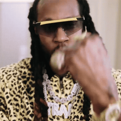 A Close Up Of A Man Wearing Sunglasses And A Necklace With The Word Trav On It GIF