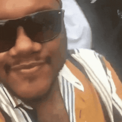 A Close Up Of A Man Wearing Sunglasses And A Striped Shirt GIF