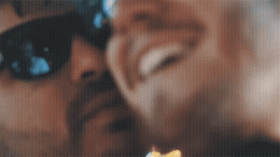 A Close Up Of A Man Wearing Sunglasses Kissing Another Man 'S Cheek . GIF