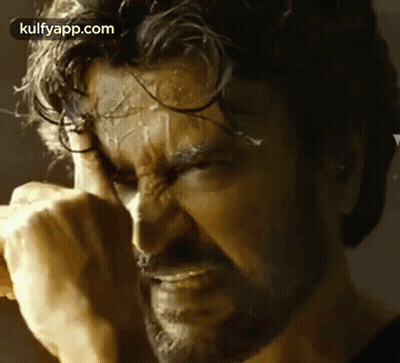 A Close Up Of A Man With A Beard Covering His Face With His Hands . GIF