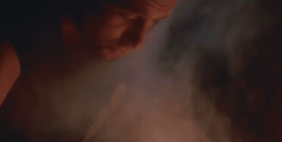 A Close Up Of A Man With A Beard Smoking A Cigarette In A Dark Room . GIF