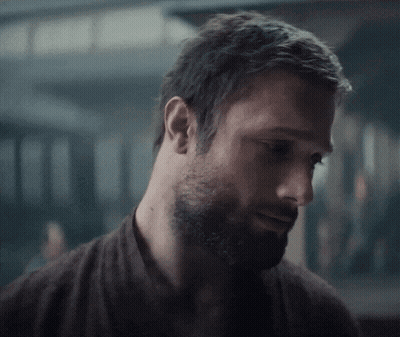 A Close Up Of A Man With A Beard Wearing A Brown Shirt GIF