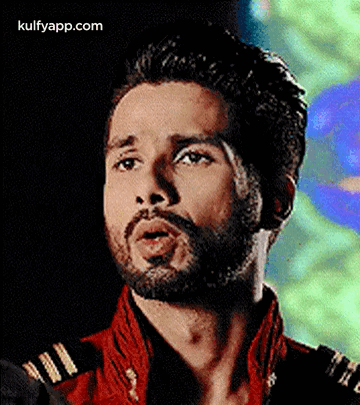 A Close Up Of A Man With A Beard Wearing A Red Jacket And A Black Shirt . GIF