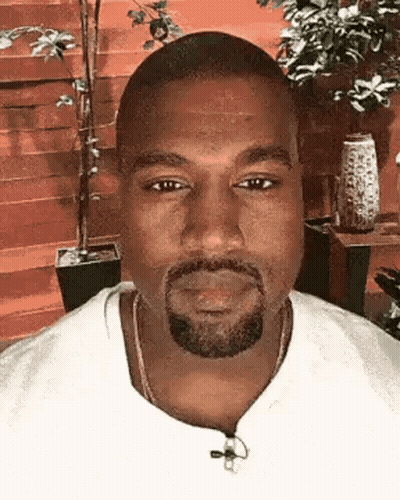 A Close Up Of A Man With A Beard Wearing A White Shirt And A Necklace . GIF