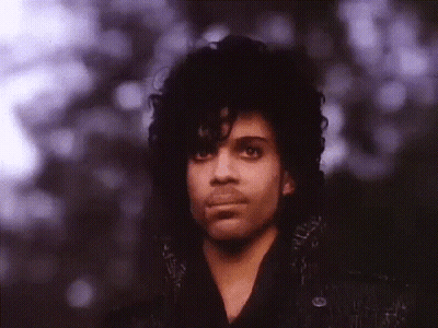 A Close Up Of A Man With Curly Hair And Purple Eyes GIF
