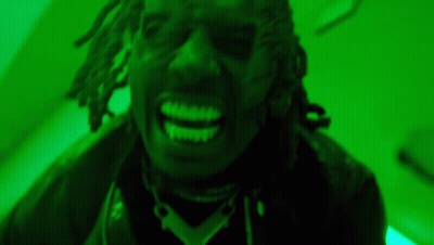 A Close Up Of A Man With Dreadlocks Smiling In A Green Room . GIF