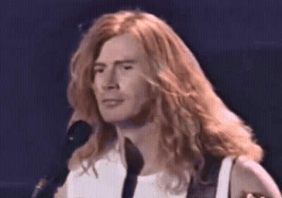 A Close Up Of A Man With Long Hair Singing Into A Microphone GIF