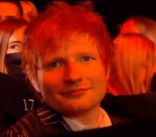 A Close Up Of A Man With Red Hair Sitting In A Crowd Of People . GIF