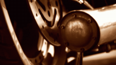 A Close Up Of A Motorcycle Wheel With A Exhaust Pipe In The Foreground GIF