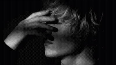 A Close Up Of A Person Covering Their Face With Their Hand . GIF