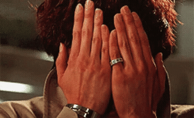 A Close Up Of A Person Covering Their Face With Their Hands And A Ring On Their Finger . GIF