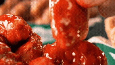 A Close Up Of A Person Dipping A Piece Of Chicken In A Sauce GIF