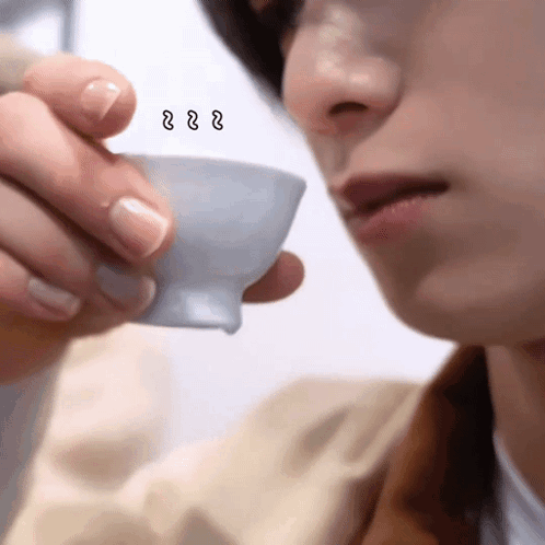 A Close Up Of A Person Drinking From A Cup With A Smiley Face On It GIF