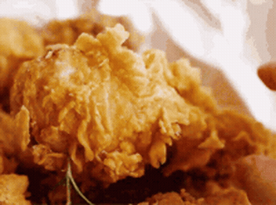 A Close Up Of A Person Eating Fried Chicken GIF