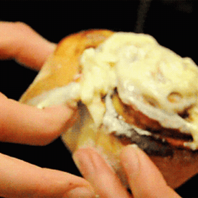 A Close Up Of A Person Holding A Cinnamon Roll With Cream Cheese GIF