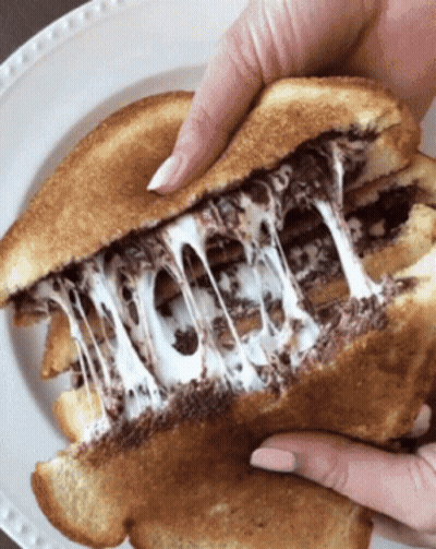 A Close Up Of A Person Holding A Grilled Cheese Sandwich On A White Plate GIF