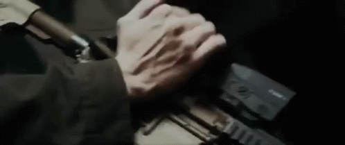 A Close Up Of A Person Holding A Gun With Their Hands . GIF