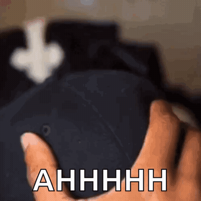 A Close Up Of A Person Holding A Hat That Says " Ahhhh " On It GIF