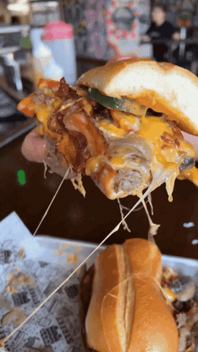 A Close Up Of A Person Holding A Sandwich With Cheese Pulled Out Of It GIF