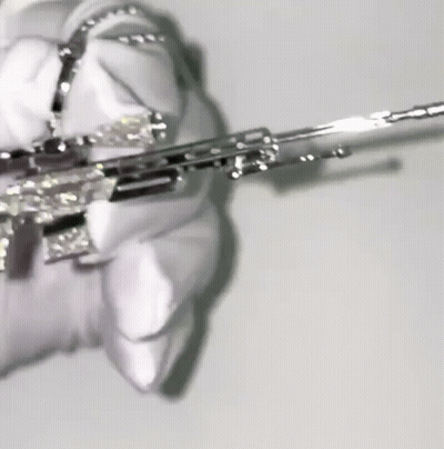 A Close Up Of A Person Holding A Silver Gun With Diamonds On It . GIF