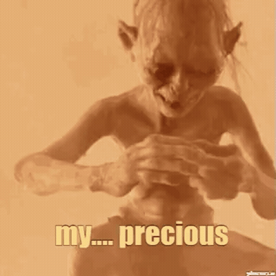 A Close Up Of A Person Holding A Small Object In Their Hand With The Words `` My Precious '' Written On It . GIF
