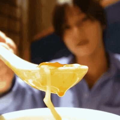A Close Up Of A Person Holding A Spoon Full Of Soup GIF