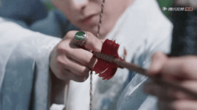 A Close Up Of A Person Holding An Arrow With A Green Ring GIF