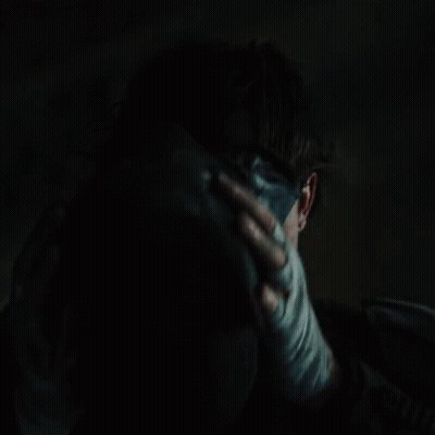 A Close Up Of A Person Holding Another Person 'S Face In A Dark Room GIF