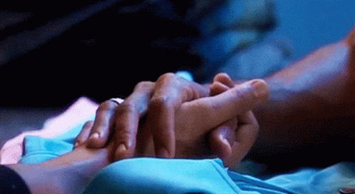 A Close Up Of A Person Holding Another Person 'S Hand In A Dark Room . GIF