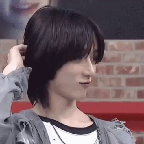 A Close Up Of A Person Holding Their Hair While Standing In Front Of A Brick Wall . GIF