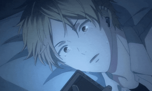 A Close Up Of A Person Laying In Bed Looking At A Cell Phone GIF