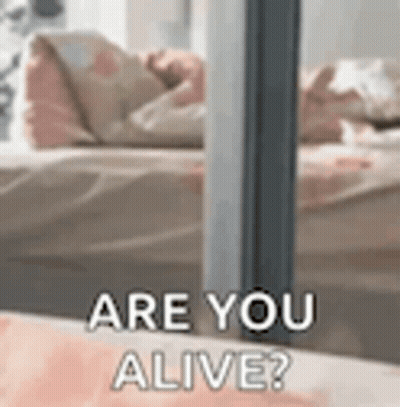 A Close Up Of A Person Laying On A Bed With The Words `` Are You Alive '' Written On It . GIF