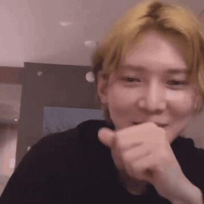 A Close Up Of A Person Making A Funny Face While Covering Their Mouth With Their Hand . GIF