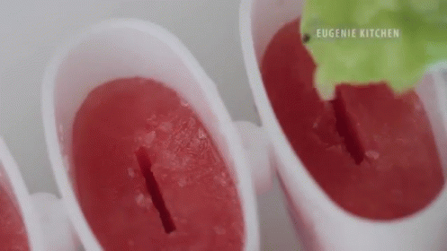 A Close Up Of A Person Making Ice Cream Popsicles With A Green Leaf . GIF