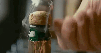 A Close Up Of A Person Opening A Bottle Of Champagne With A Cork Sticking Out Of It . GIF