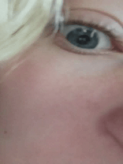 A Close Up Of A Person 'S Blue Eye With A Reflection Of A Person 'S Face . GIF
